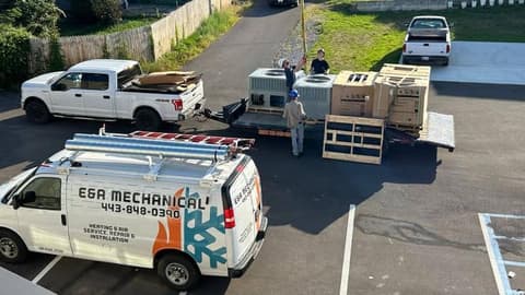 Overhead view of the E&A Mechanical van and a pickup in a parking lot with new crated equipment staged on pallets