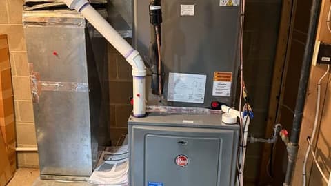 Newly installed Rheem furnace with fresh sheet metal plenum and flue pipe in a basement
