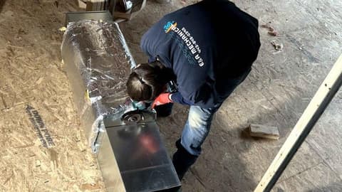 E&A technician in a company shirt assembling new sheet metal ductwork on a plywood subfloor